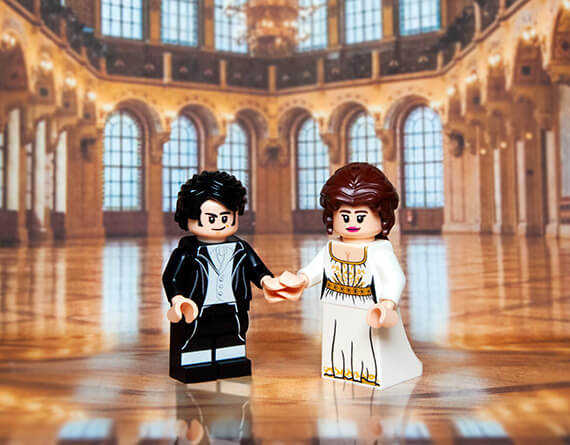 two custom minifigs from pride and prejudice made from LEGO in a large, ornate hall with high ceilings and large windows.